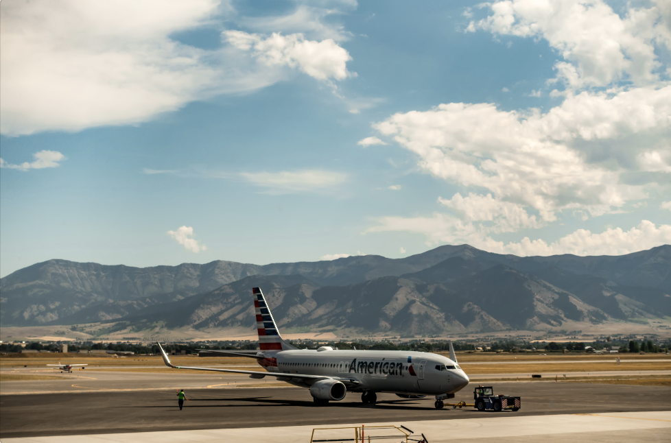 airplane on airport runway with mountains in the background